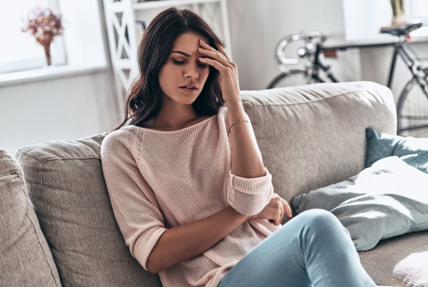 Young woman experiencing headache and fatigue at home.